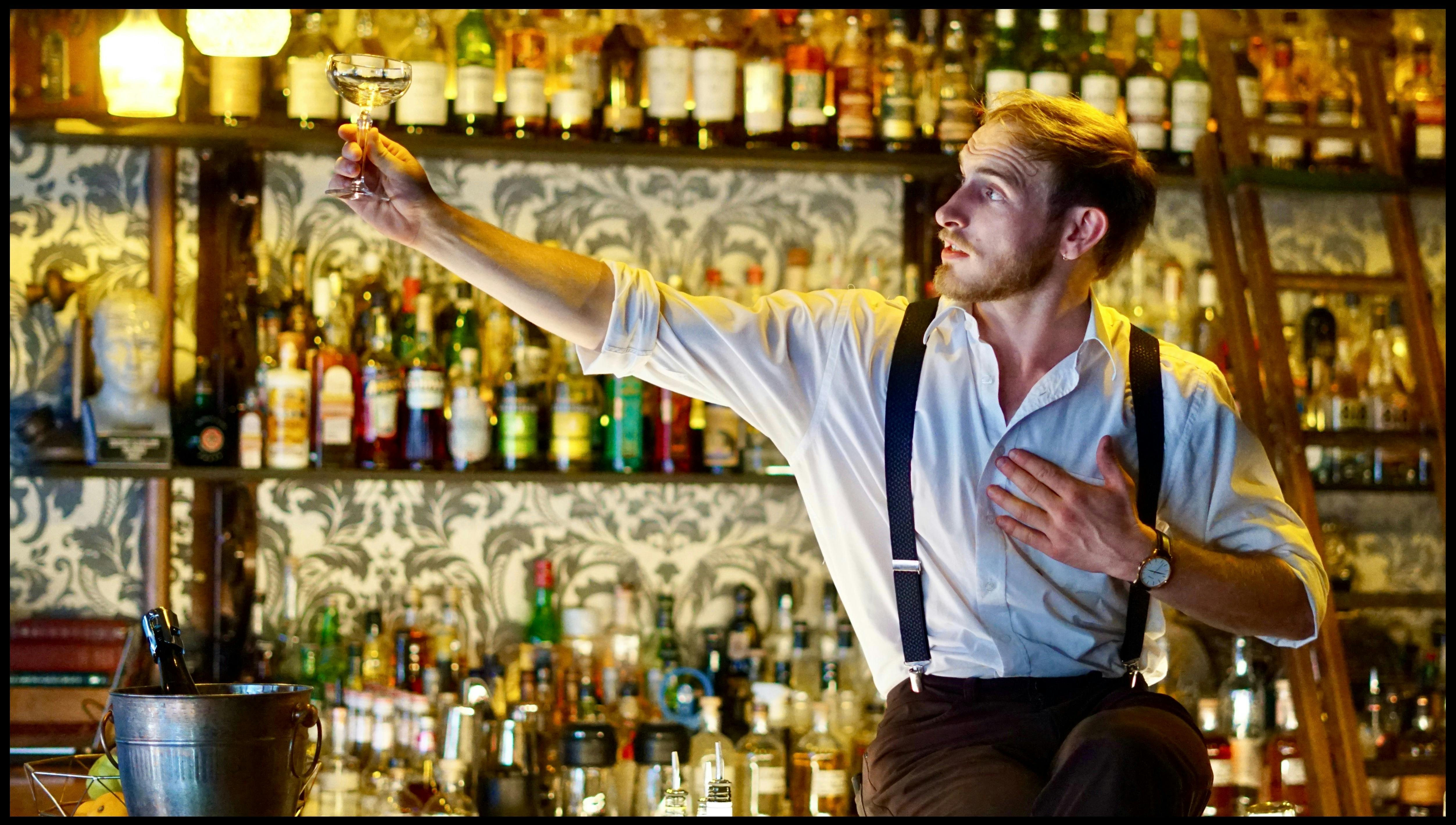 a man sits on a bar with his arm stretched out looking at his own hand