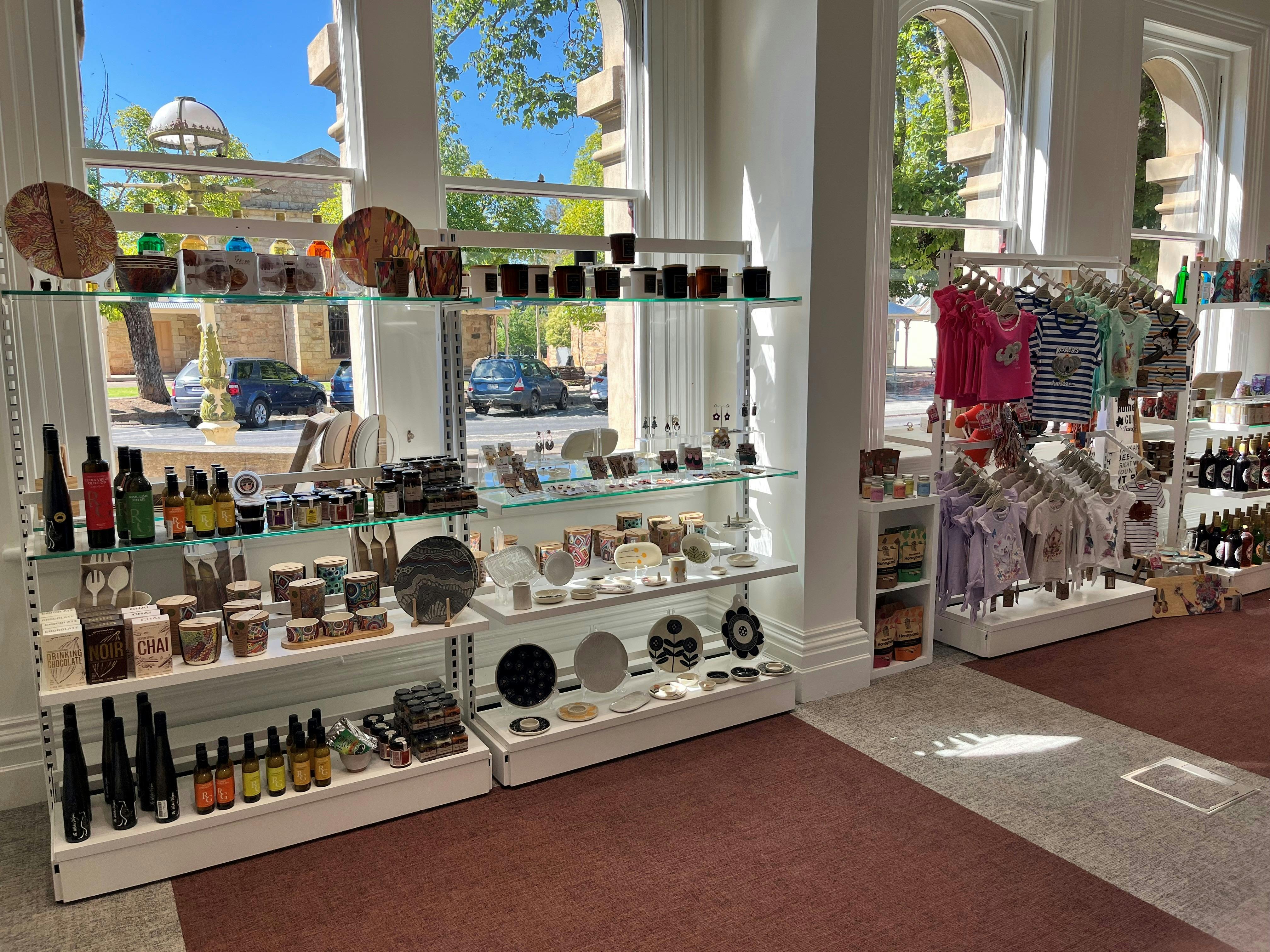bright windows, retail shelving in front with children's clothing, candles , produce and giftware