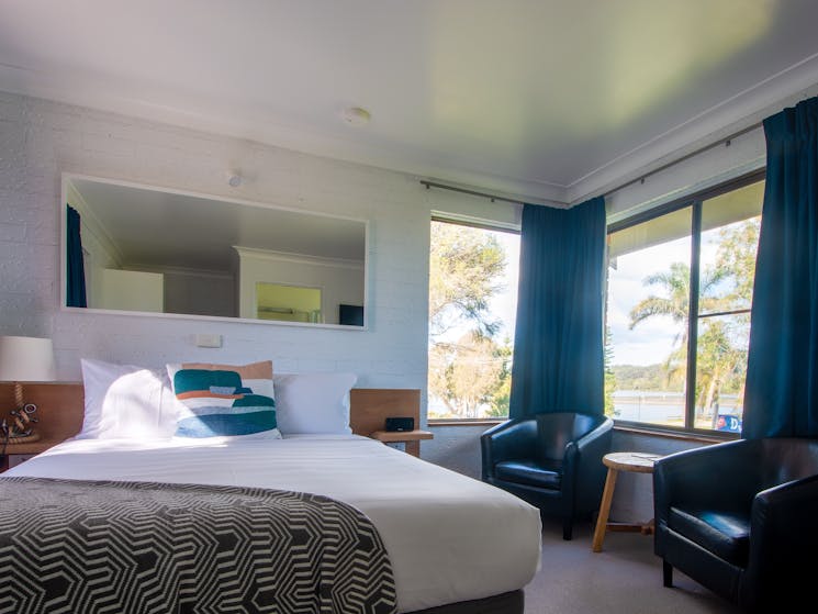 The deluxe room offers a comfy queen bed, seating area, and kitchenette facilities.