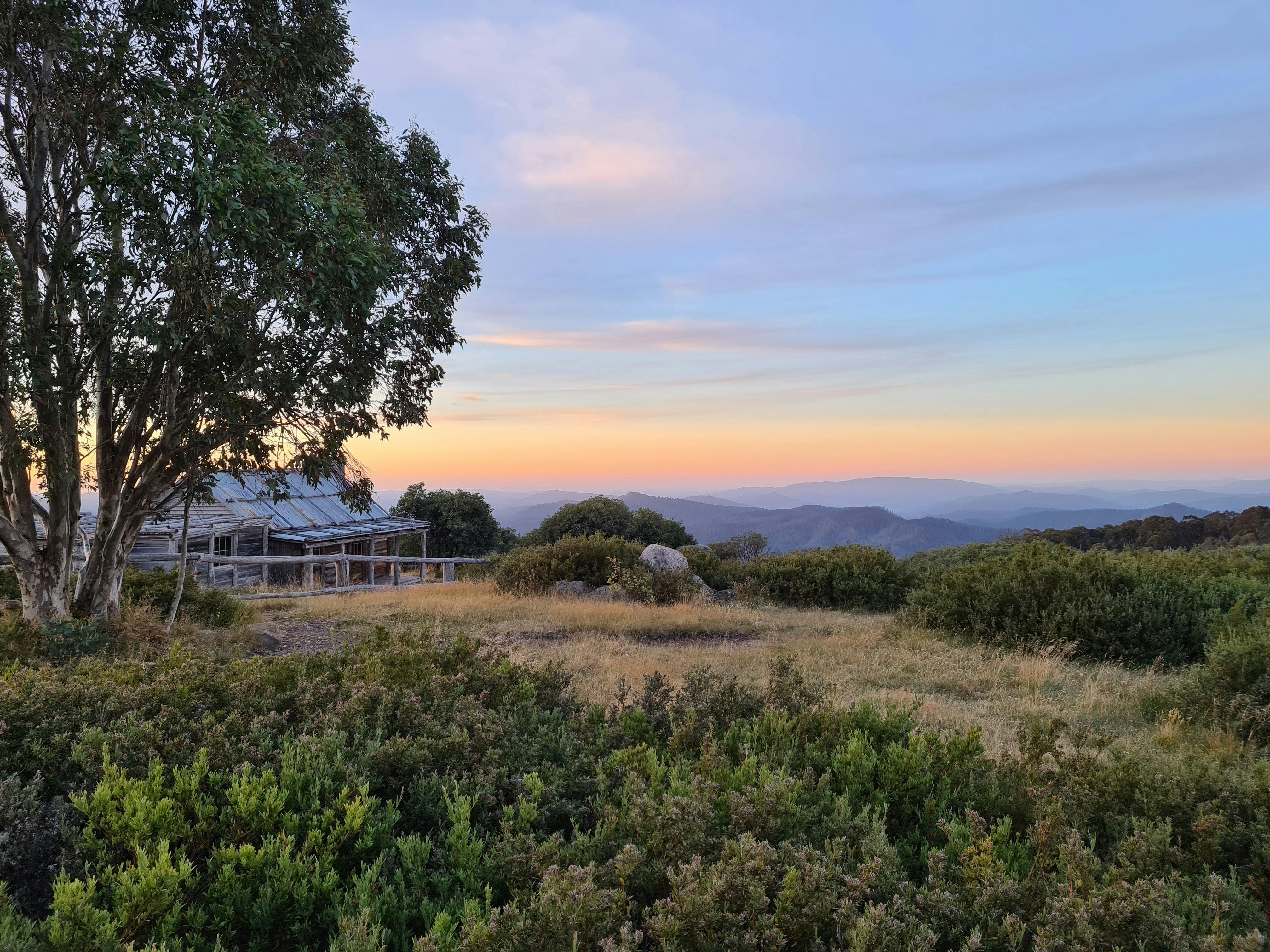 Craig's Hut and the magnificent views of the surrounding mountains with soft orange and blue sky.