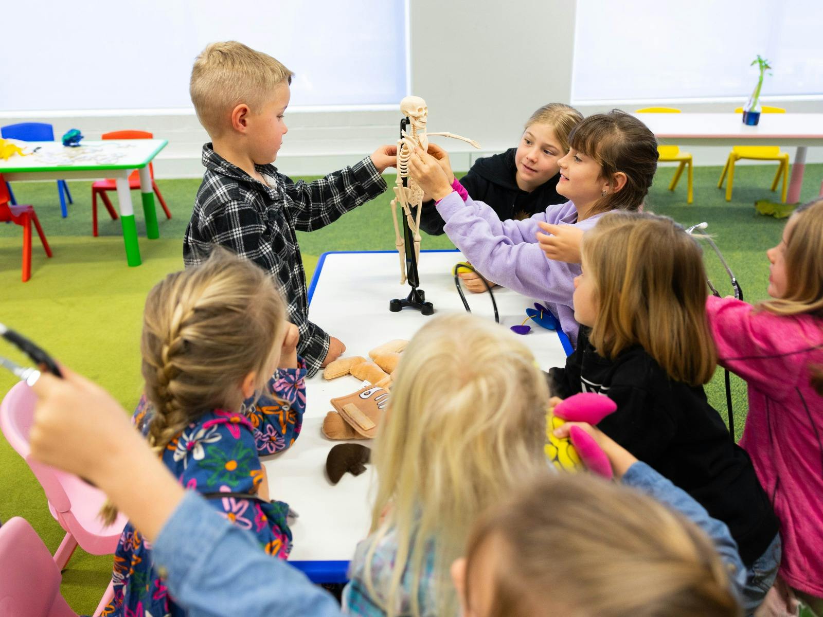 A group of children exploring a miniature skeleton