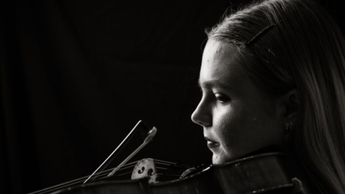 Black-and-white portrait of a violist in profile, looking toward the light