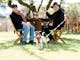 two people at a table drinking wine with their dog standing by the table
