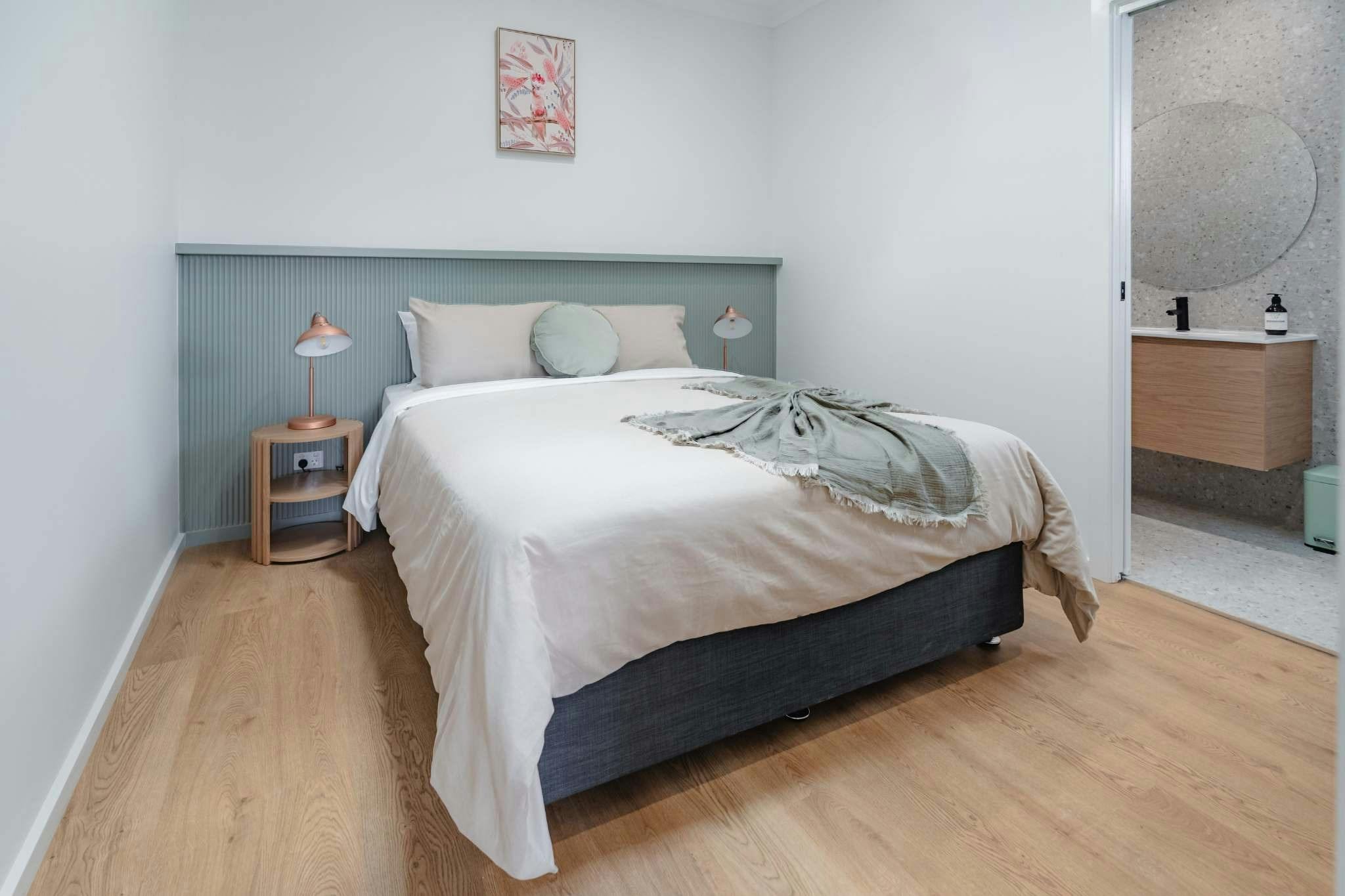 Bedroom with neutral bedding, side tables and door with ensuite