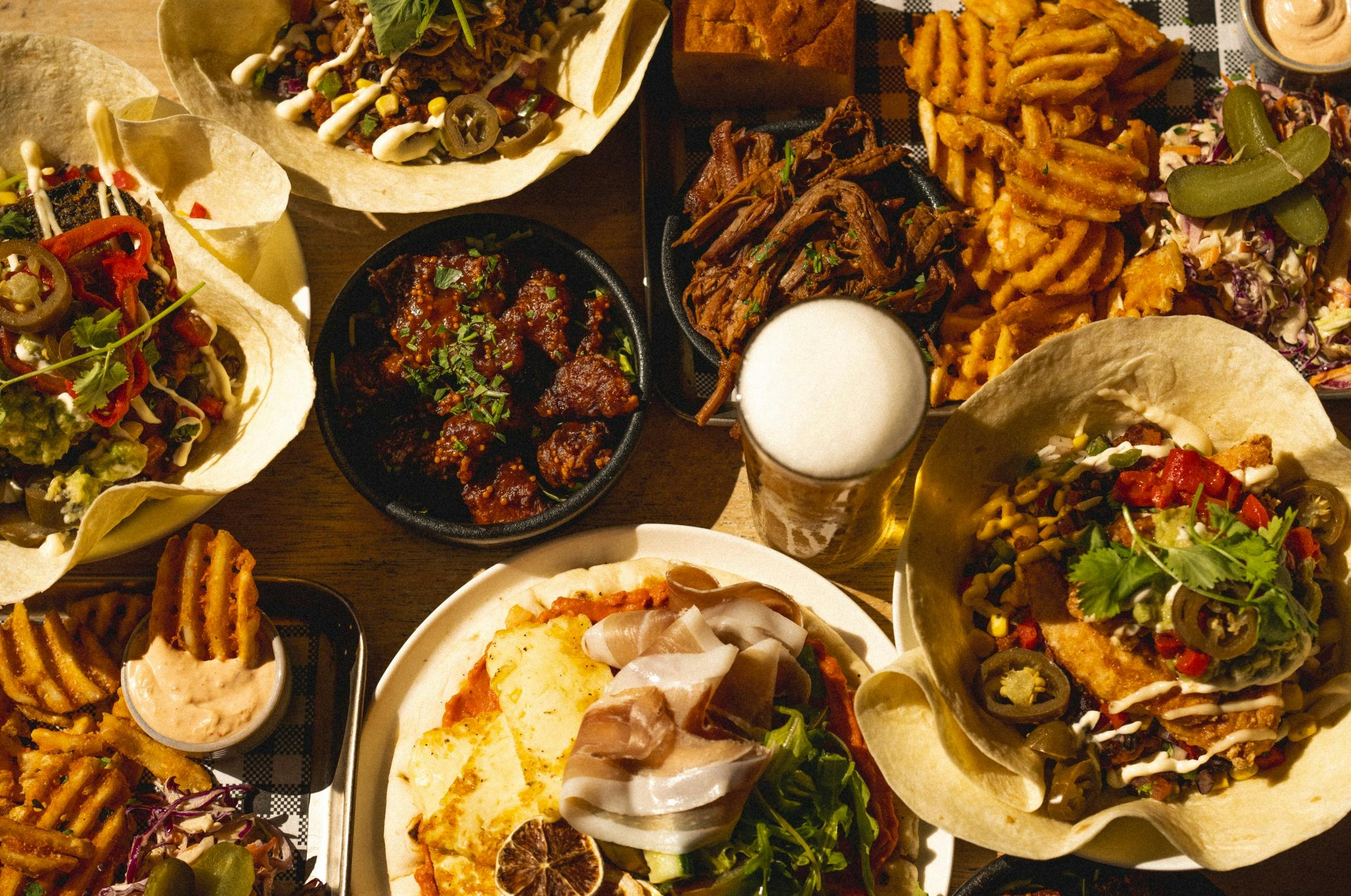 Spread of burrito bowls and share plates with beer
