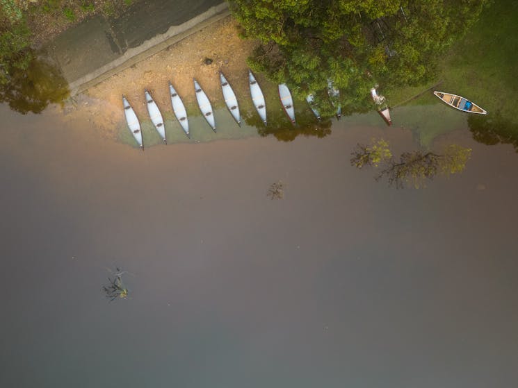 an aerial photo of a fleet of canoes on shore