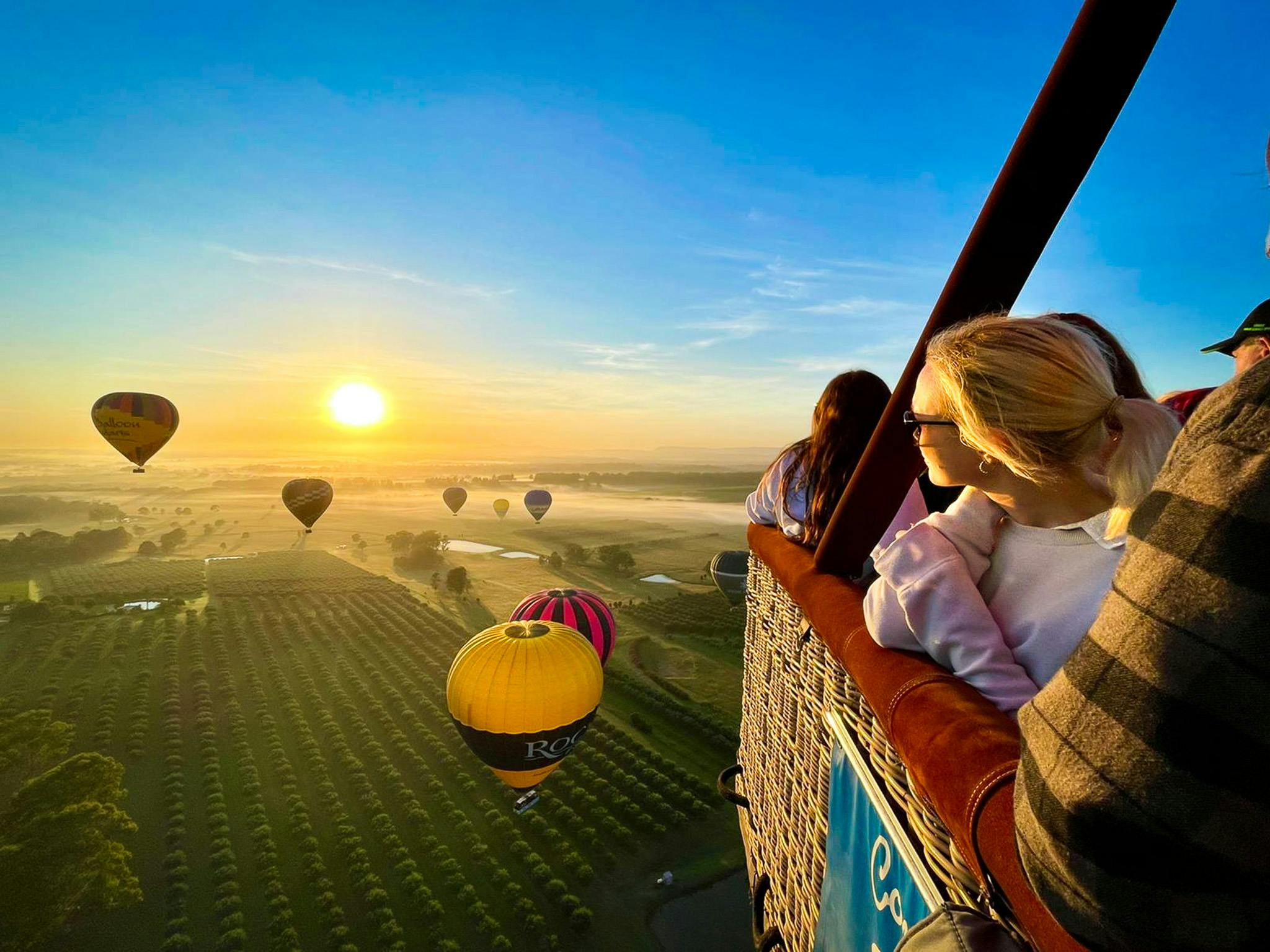 日出时分，乘客们观看其他热气球漂浮在猎人谷葡萄园上空。