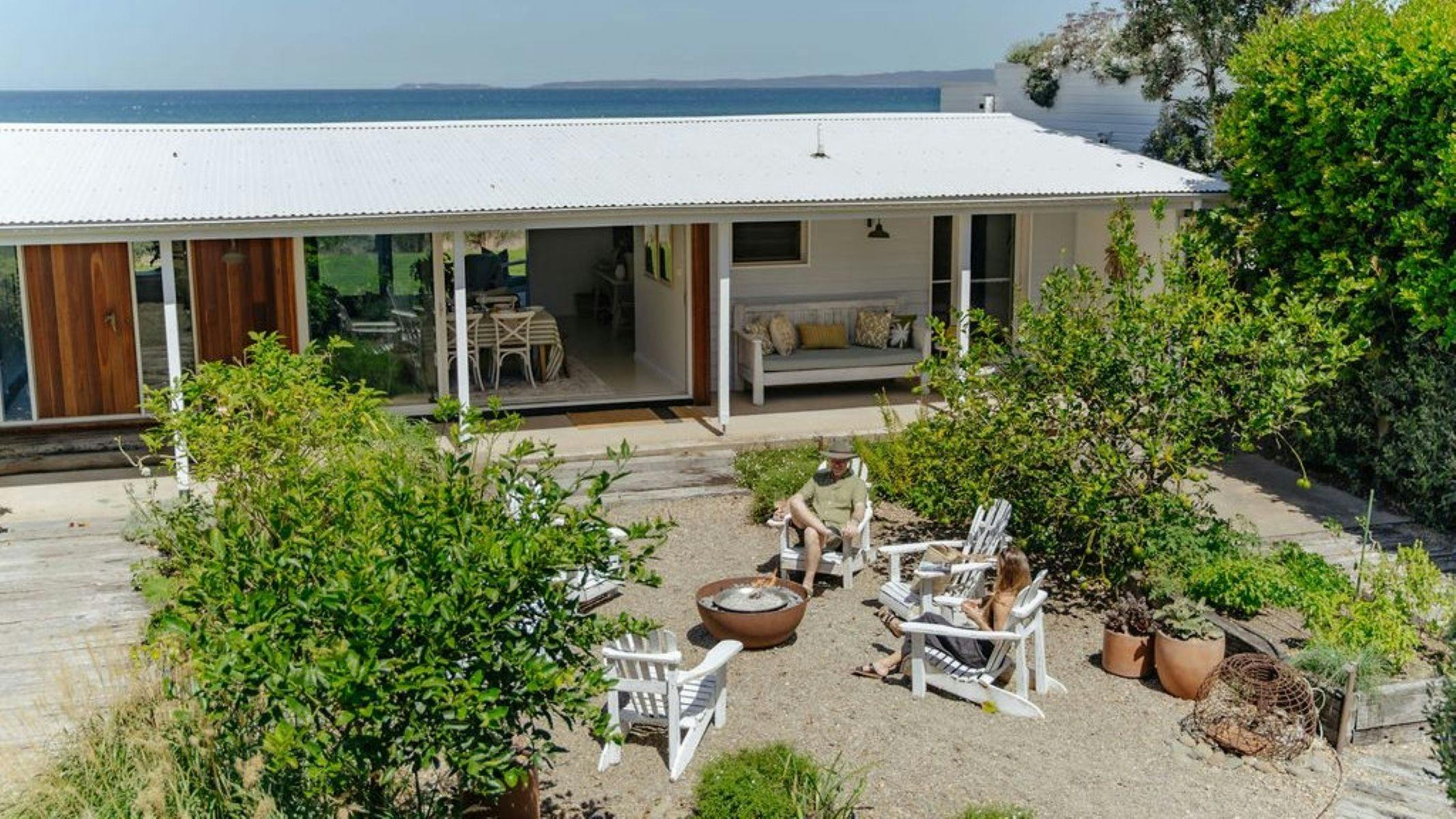 View of outside firepit area, guests are siting around the fire and enjoying a drink.