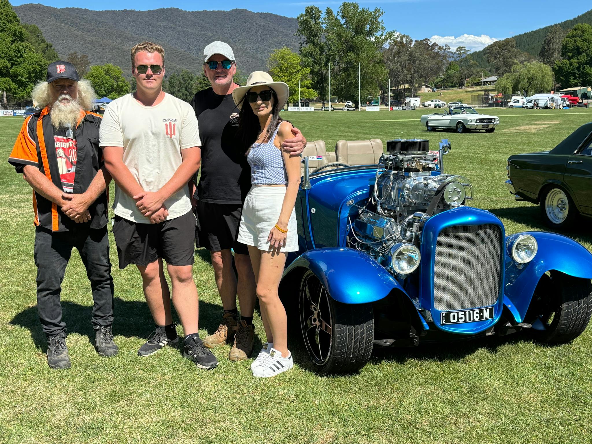 Four people posing next to a car