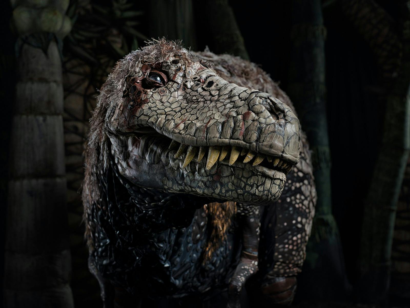 Close-up of a detailed dinosaur-like creature with scaly skin, sharp teeth, and a feathered head, fa