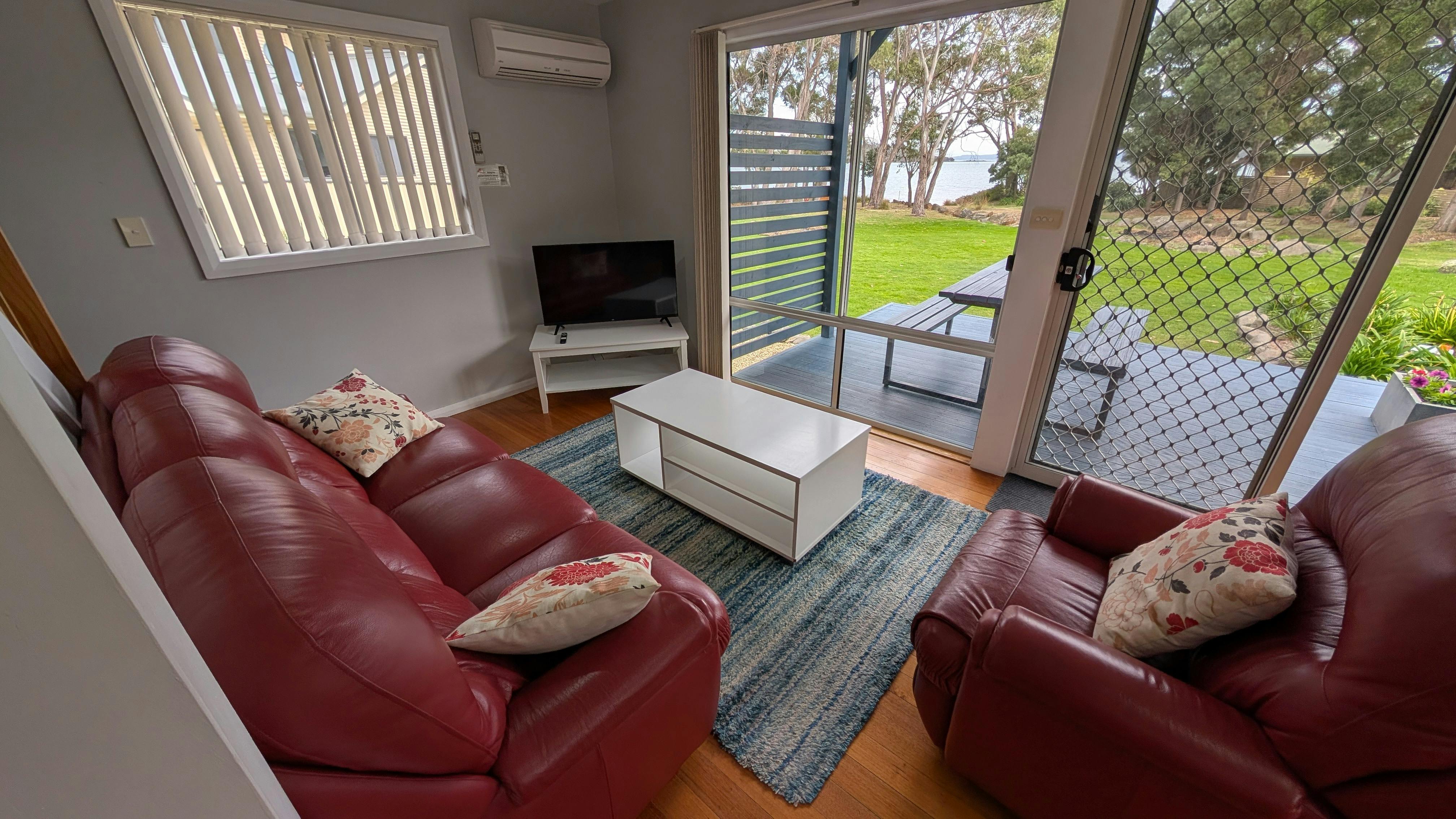 Living area with lounges, television, outdoor deck and water views.