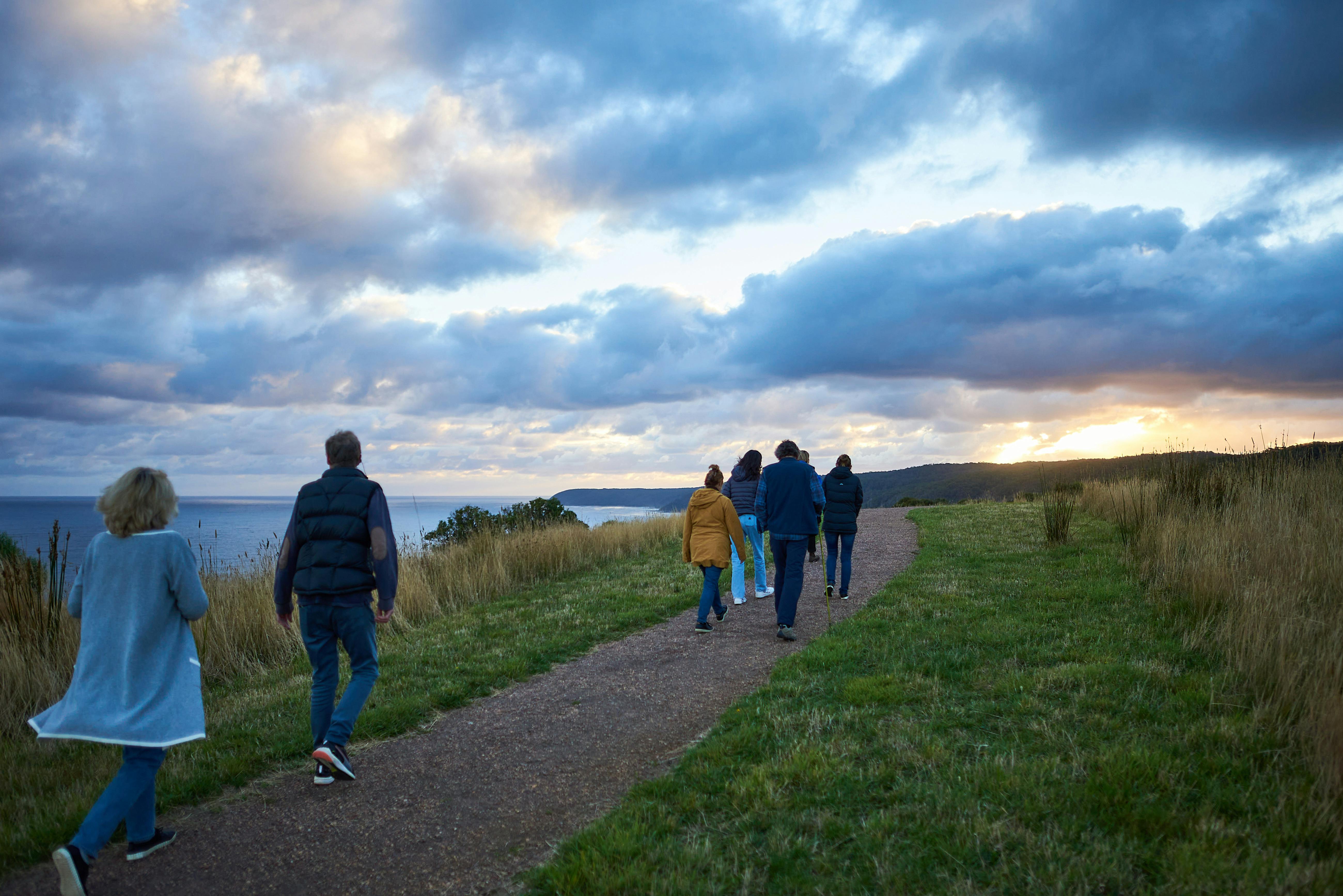 People walking along a path at sunset