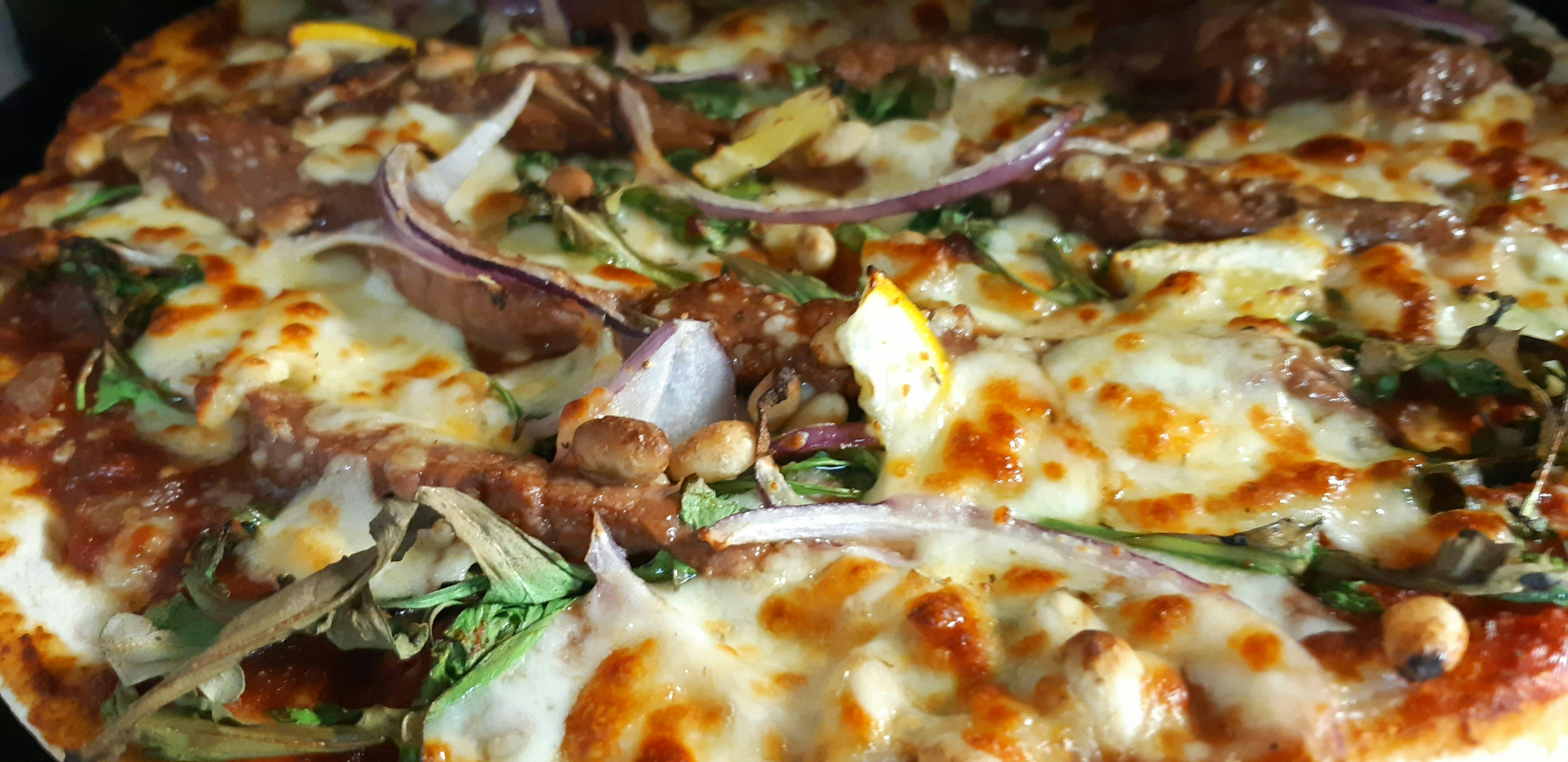 Close up of pizza with beef, onion, rocket, lemon slices and cheeseket