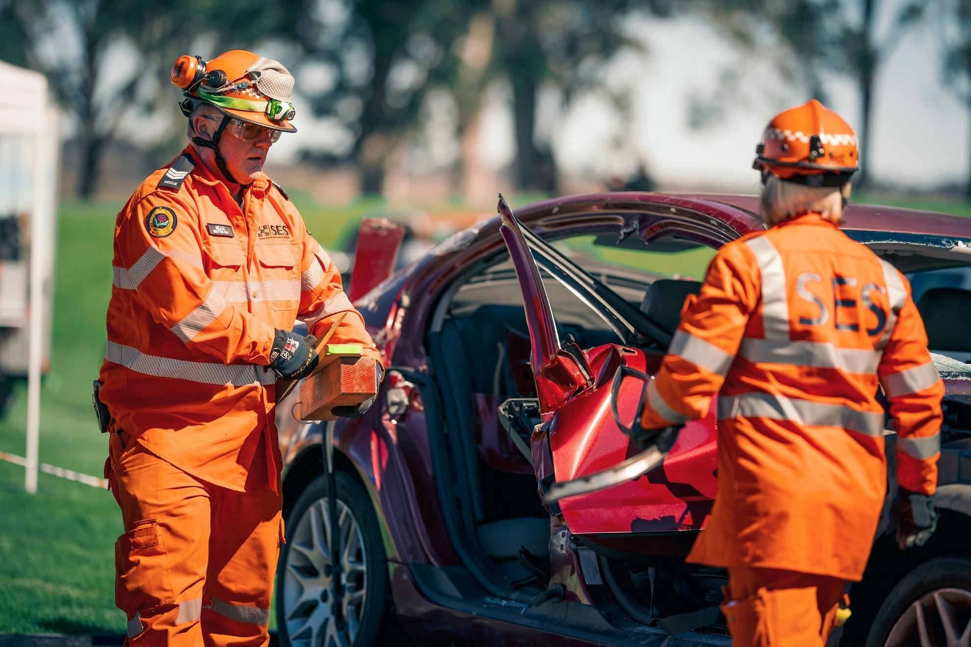 Two NSW SES Officers are showing guests how they remove the doors on a vehicle and extract a patient