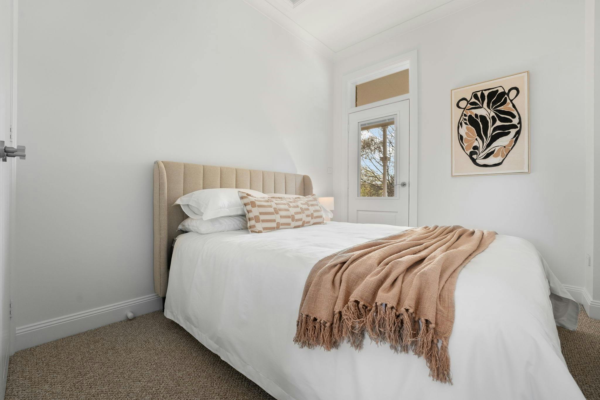 Bedroom with queen bed, artwork and a door leading to balcony
