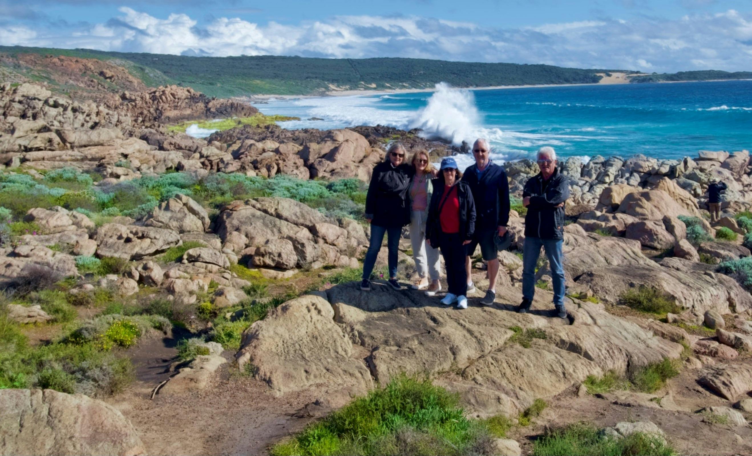 people standing on rocky outcrop with waves crashing behind them