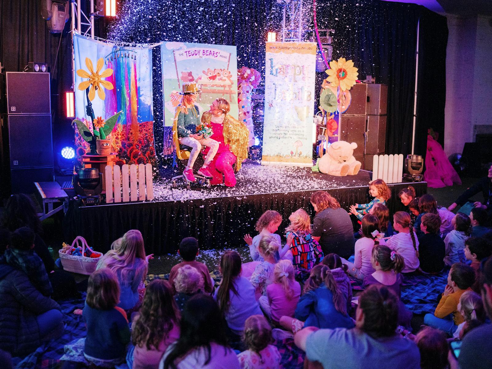 Colourful lit stage with children's performer and crowd of young children audience members