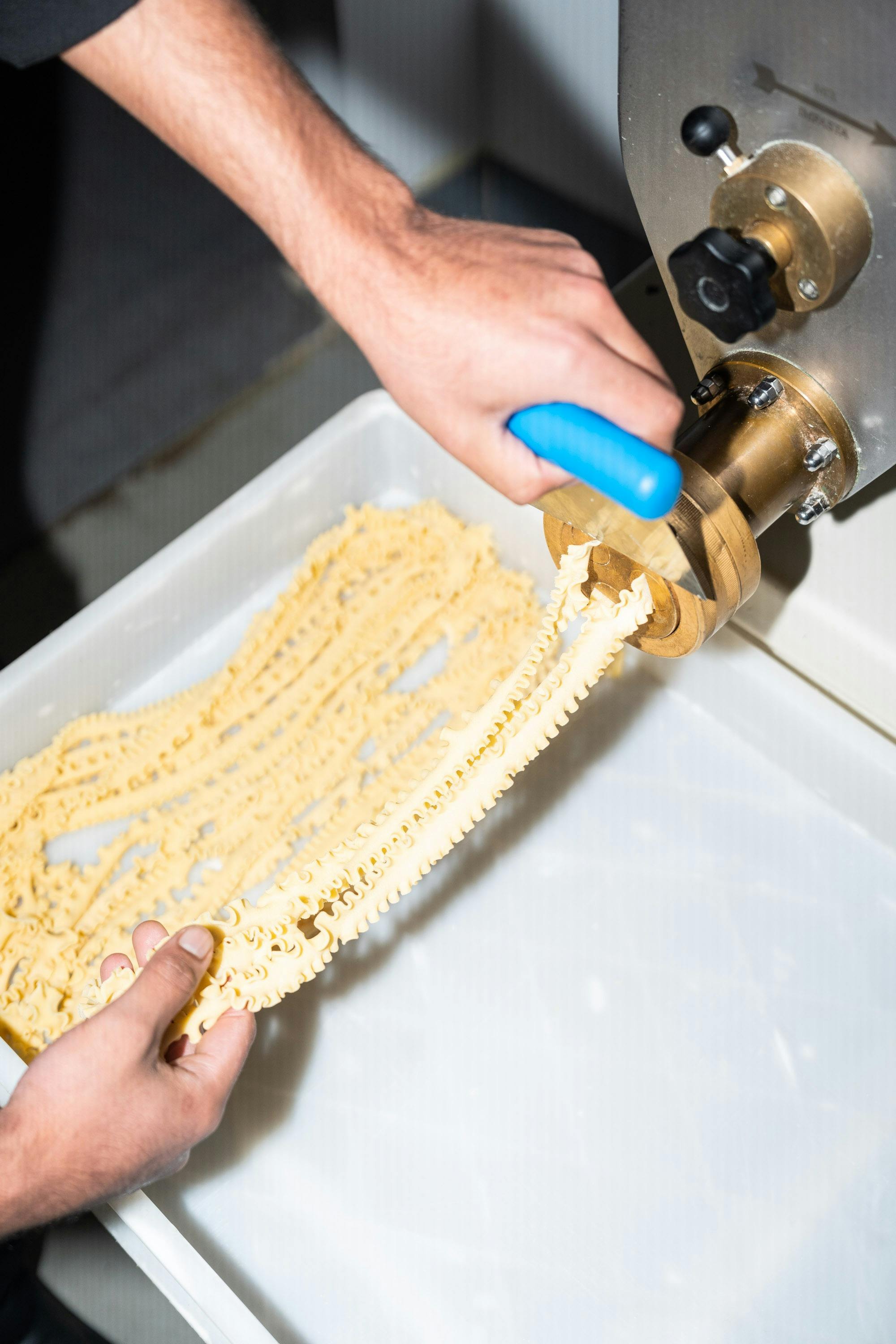 Fresh pasta being hand cut off the machine