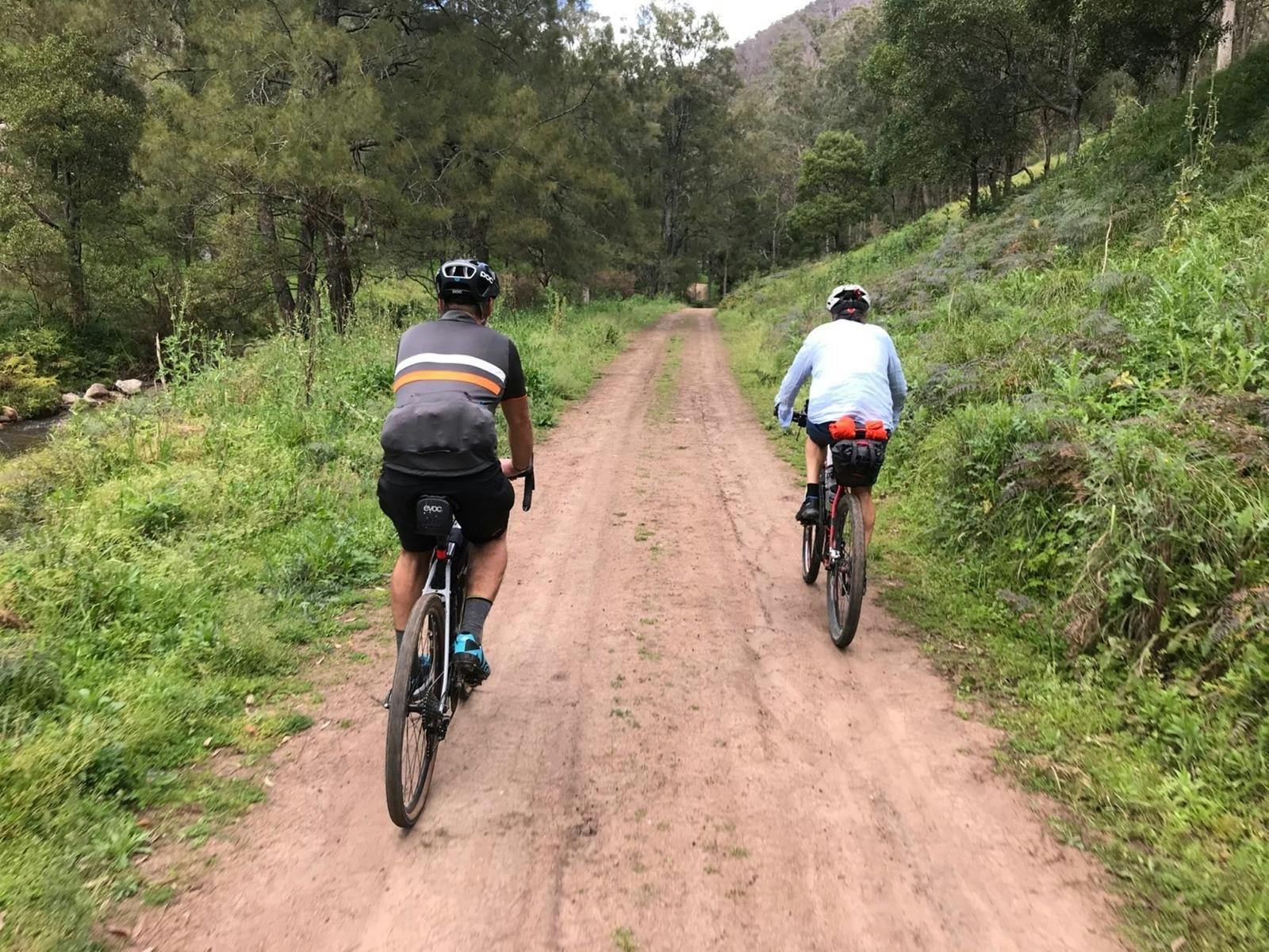 2 cyclists on dirt road behind house