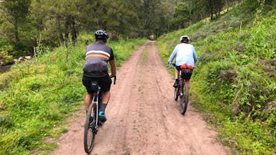 2 cyclists on dirt road behind house