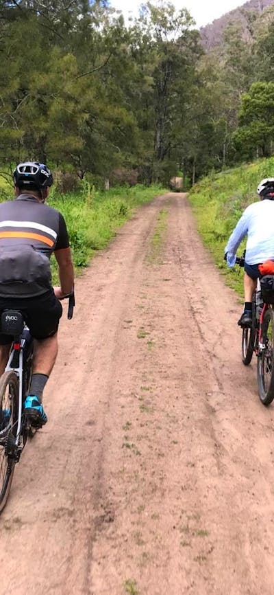 2 cyclists on dirt road behind house