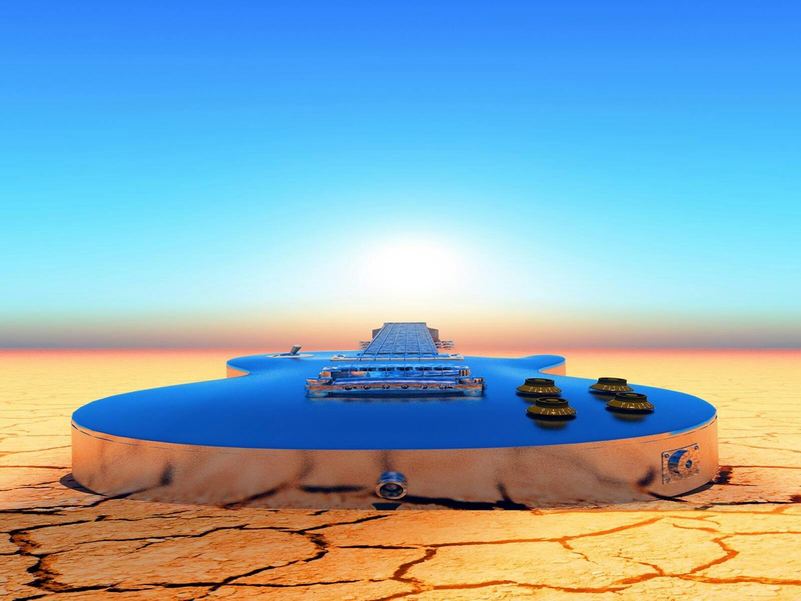 A blue guitar is lain on a desert ground with the sun on the horizon and blue sky