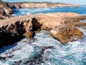 A drone shot of the coastal trail with tour vehicle on the end of rocky cliffs