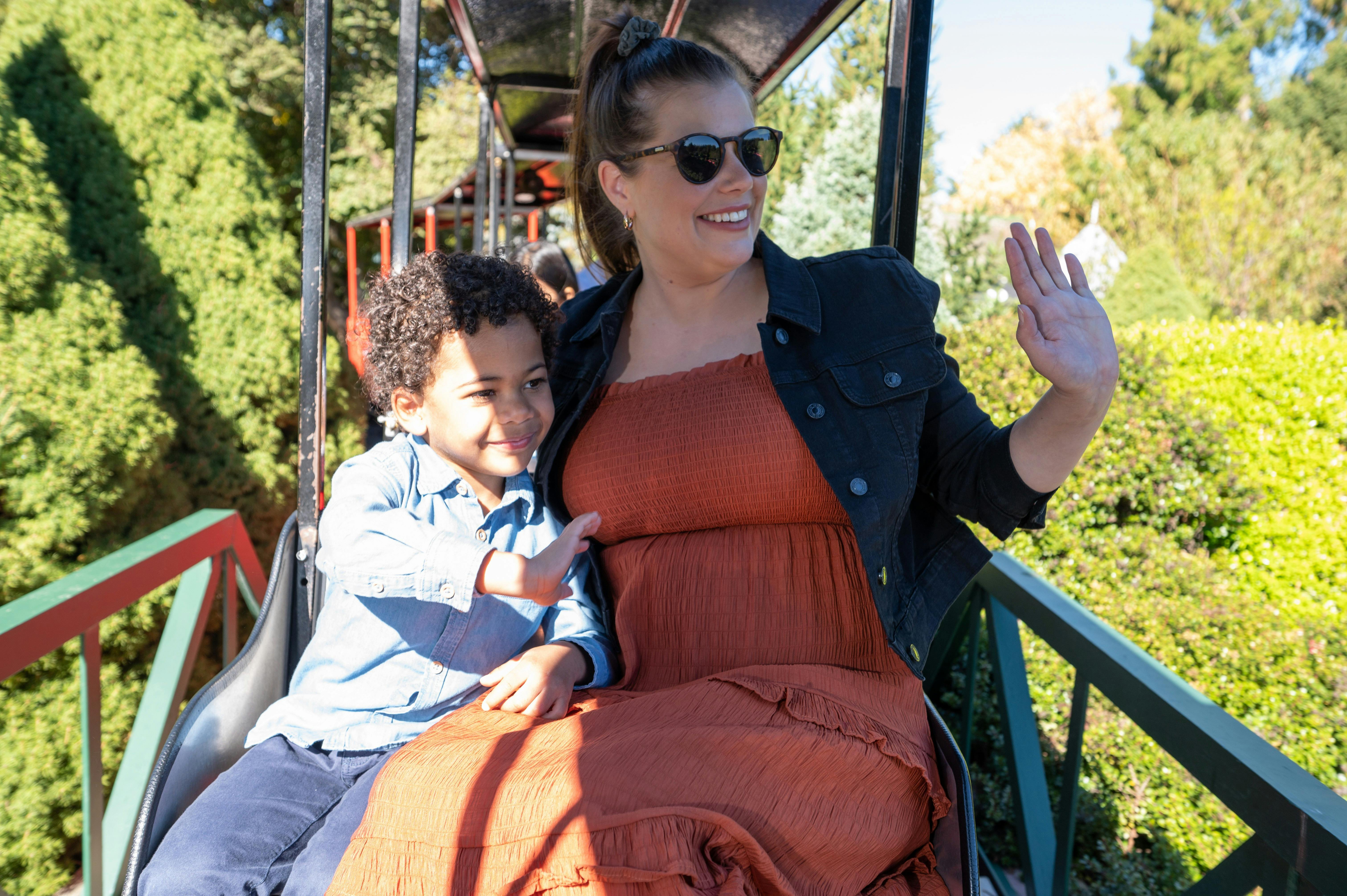 A mother and son ride a steam train and wave to others