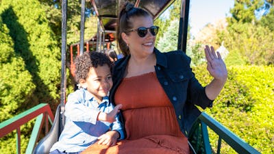 A mother and son ride a steam train and wave to others