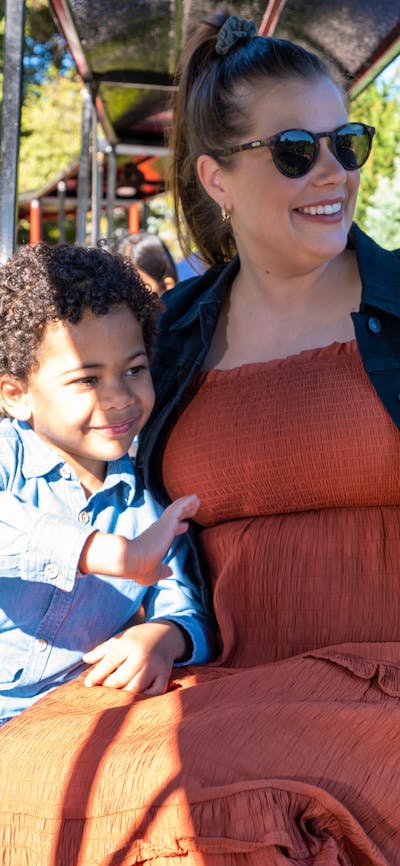 A mother and son ride a steam train and wave to others