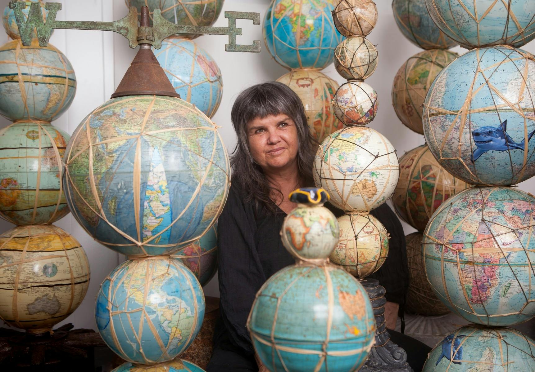 The artist Karla Dickens is seen in the centre of a sculpture made of globes.