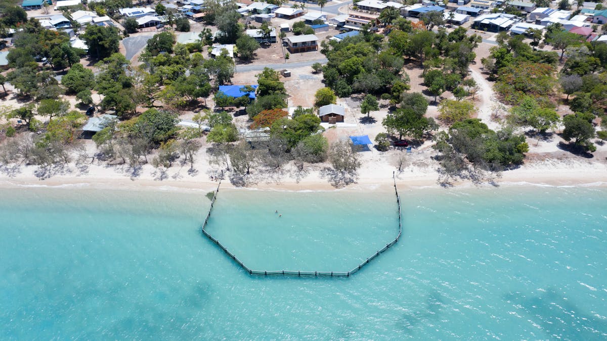 Aerial view of Dingo Beach town with swimming net and homes in the background