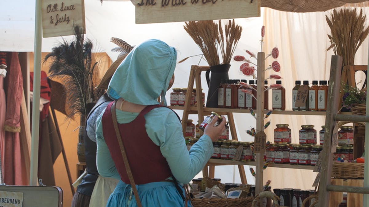 Women browsing a market stall with sign reading 'Wild West Pantry'