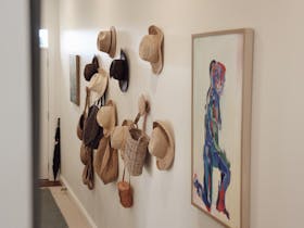 Hallway with a collection of hats, hanging bags and framed artwork.