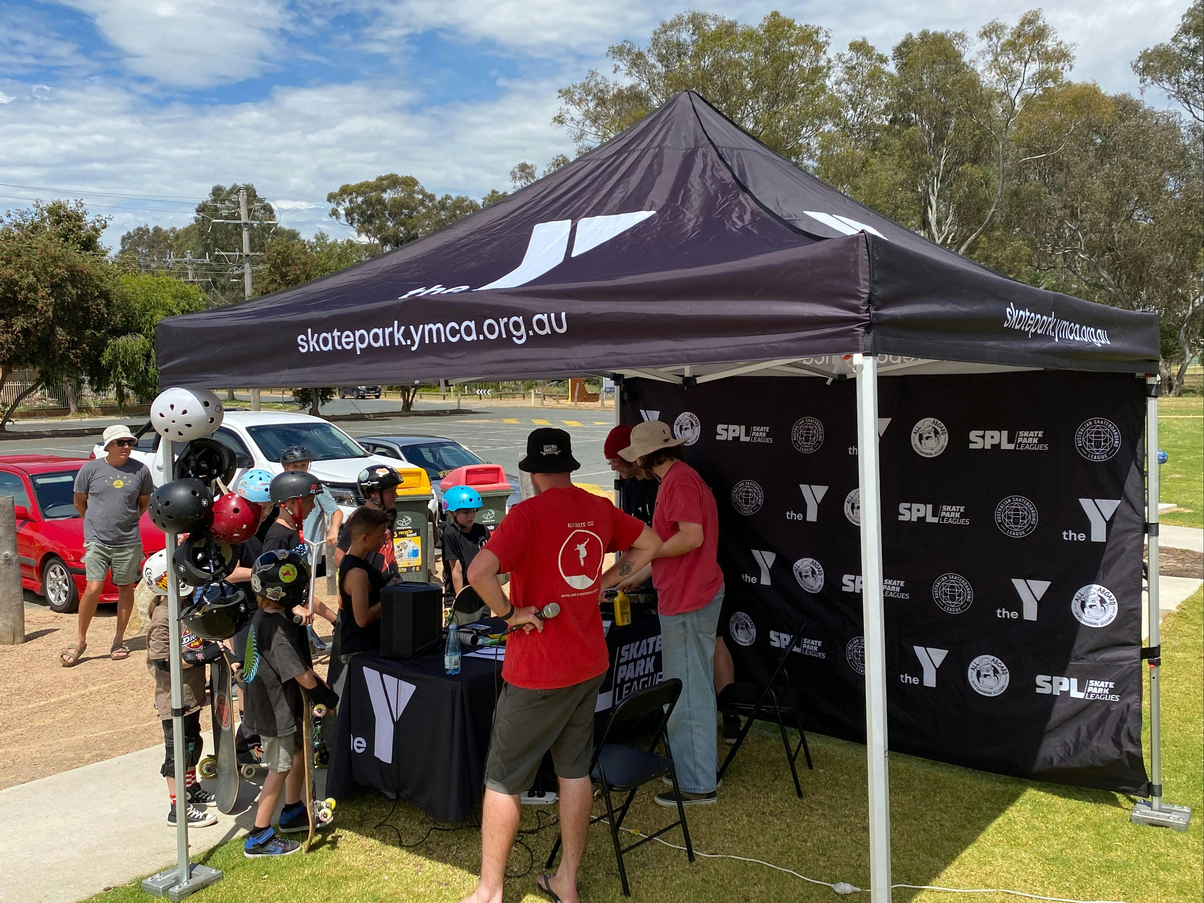 Marquee set up with table registering participants in event, helmets, skateboards