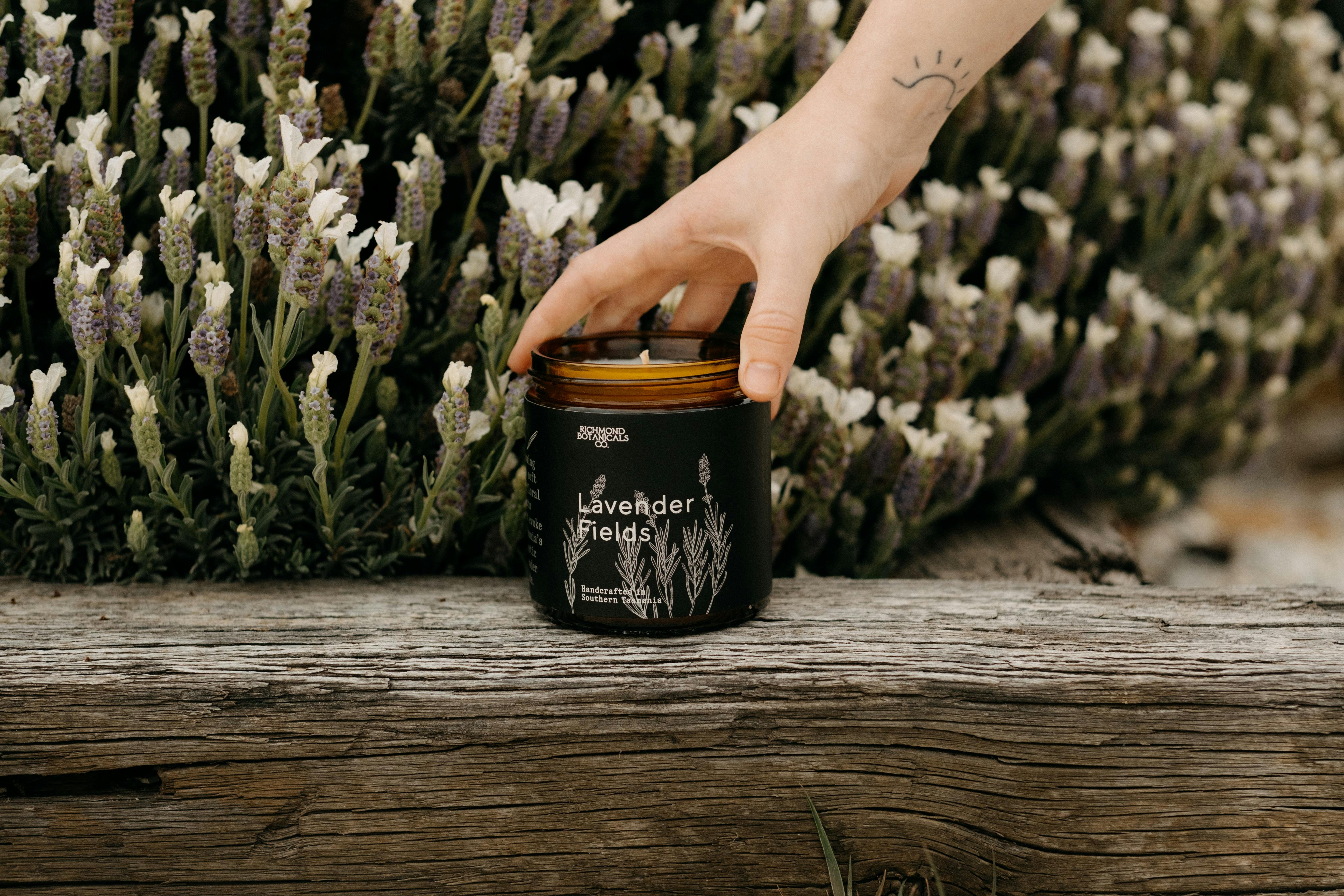 Hand reaches for candle with lavender behind