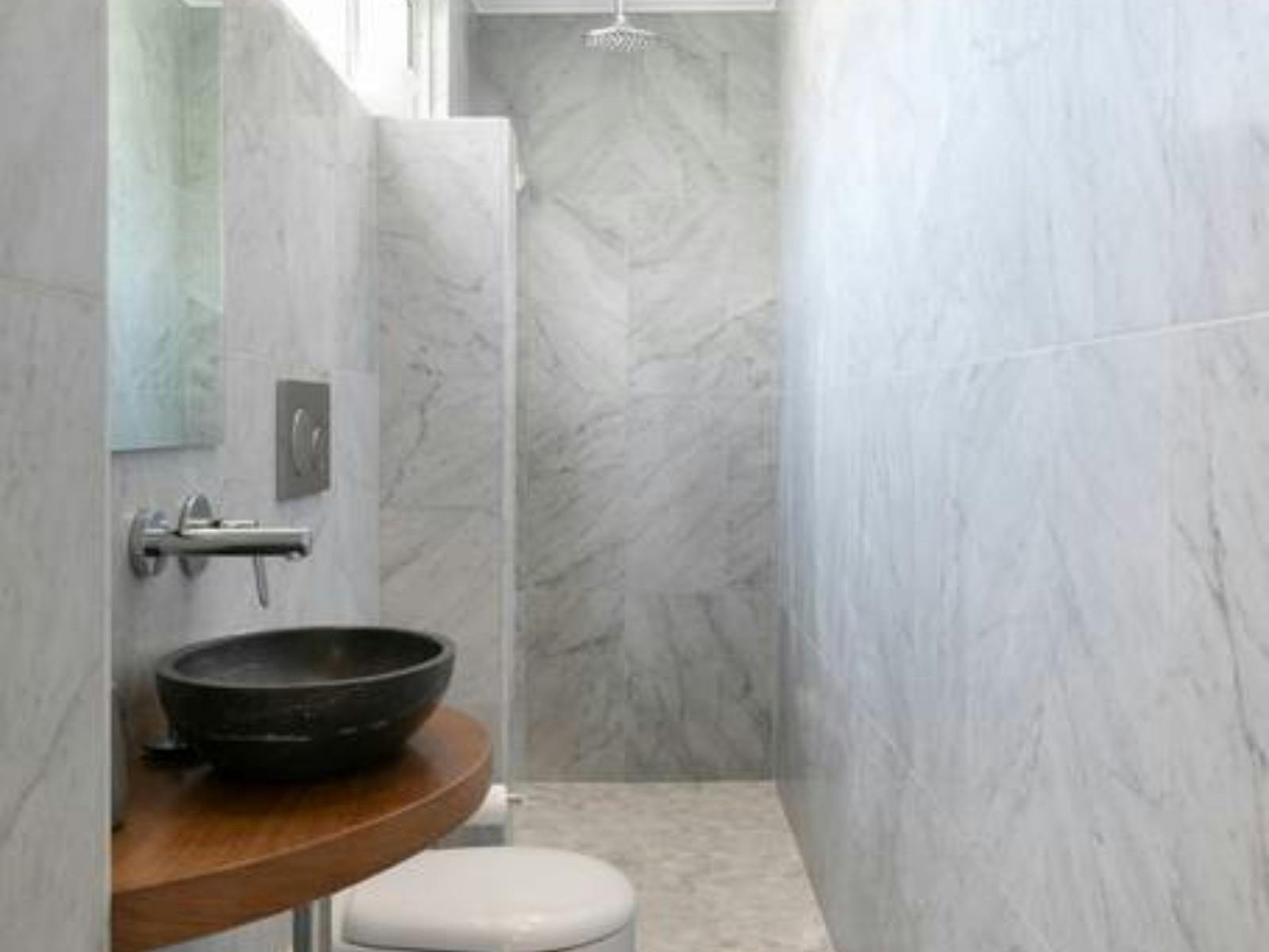 Contemporary bathroom featuring marble walls, a stone sink, and minimalistic design.