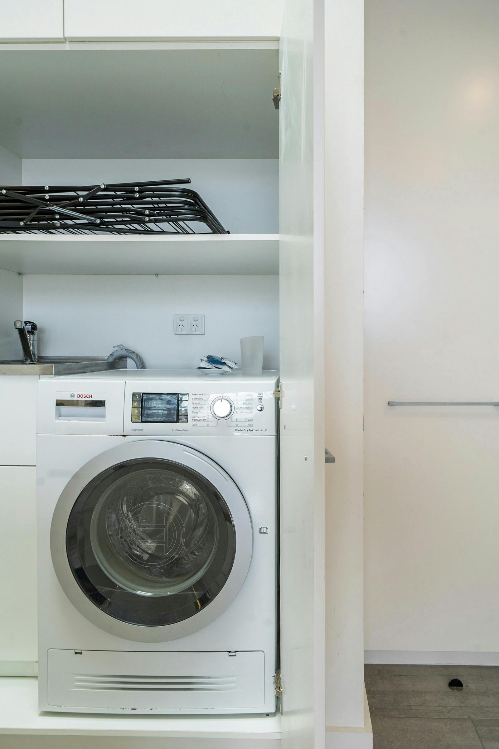 Sleek bathroom with glass shower, and a well-equipped laundry area with washing machine.