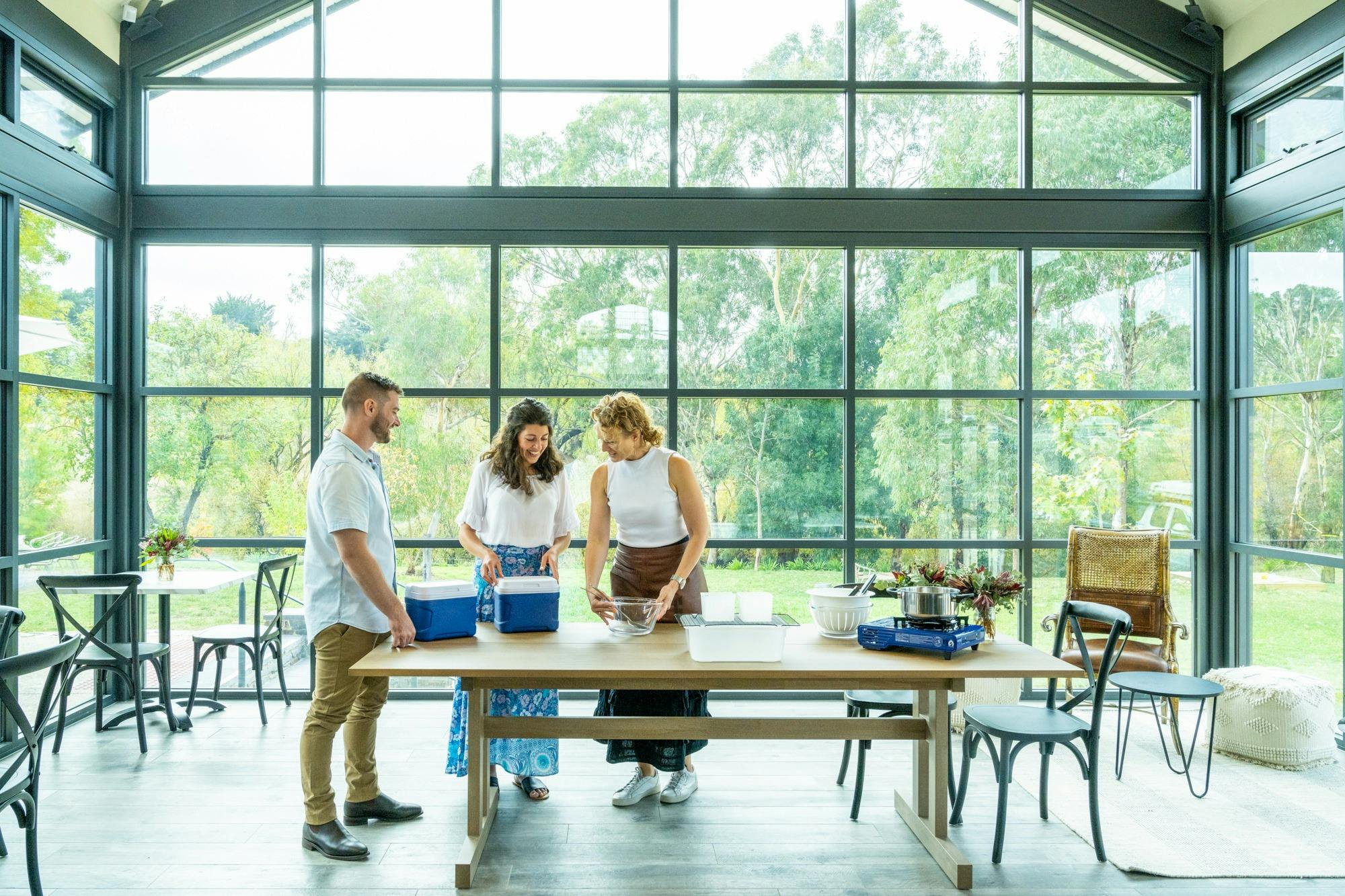 3 people standing around table in a large glass building
