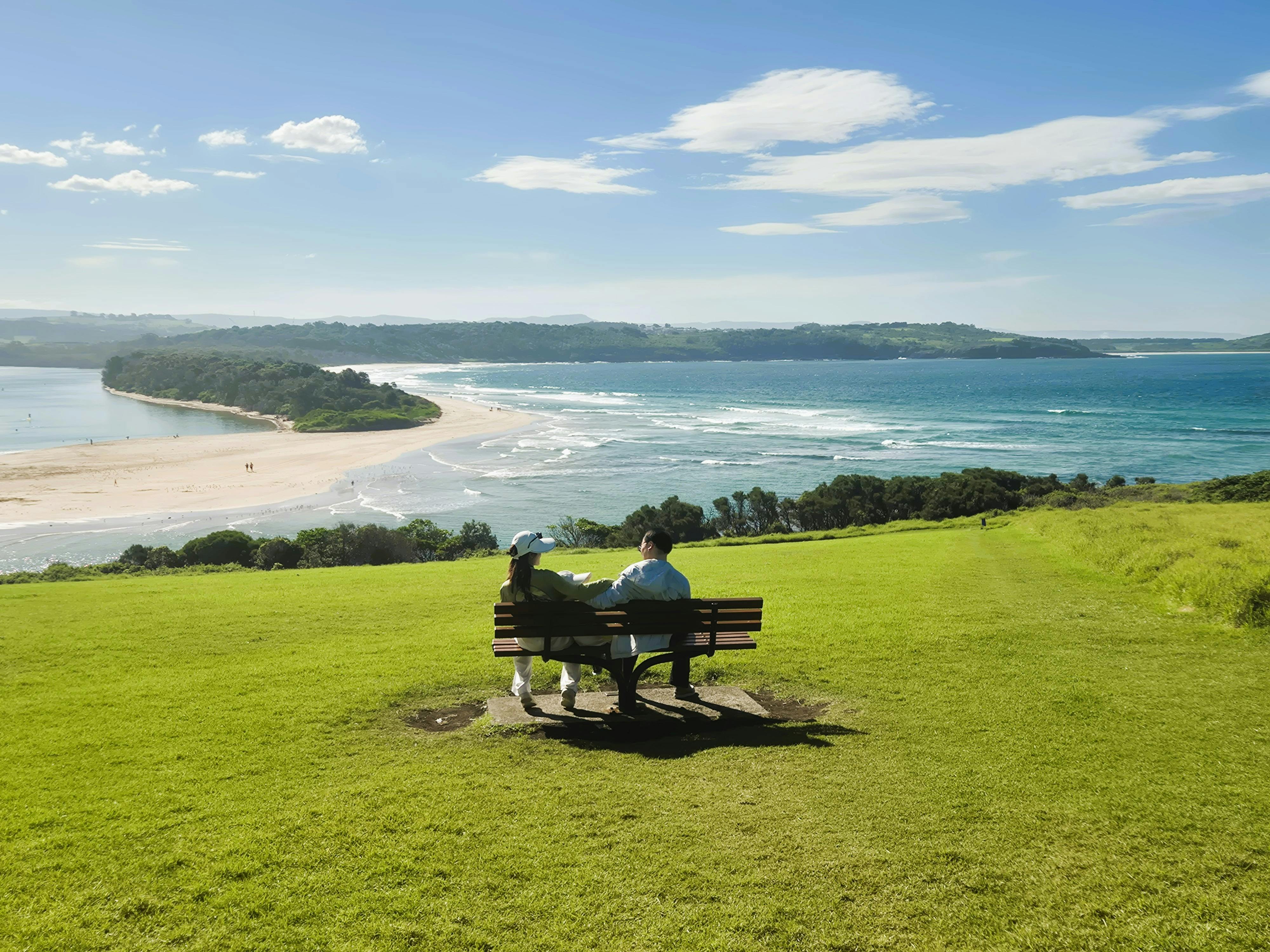 Two people seated looking out to the Kiama coastline