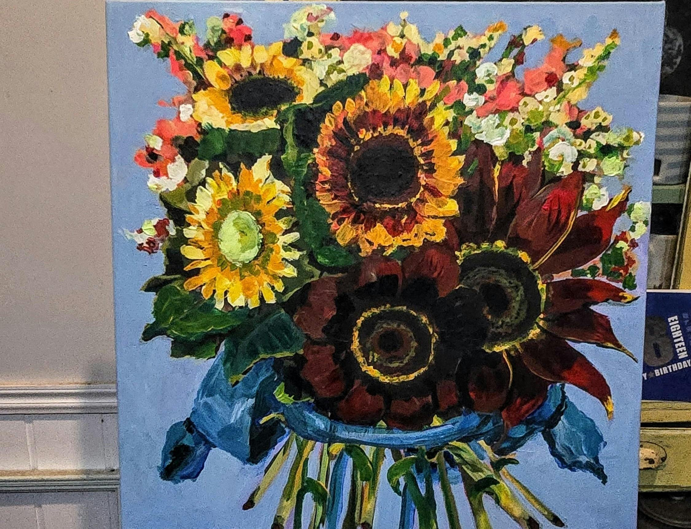 Clear vase with colourful sunflowers and other bright blooms