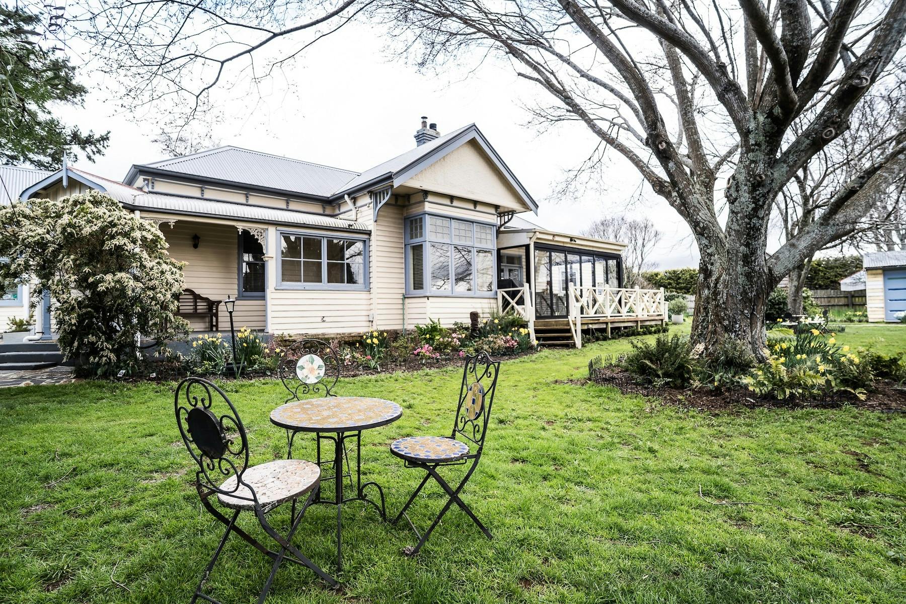 Glencoe farmhouse and garden with outdoor seating beneath a mature tree