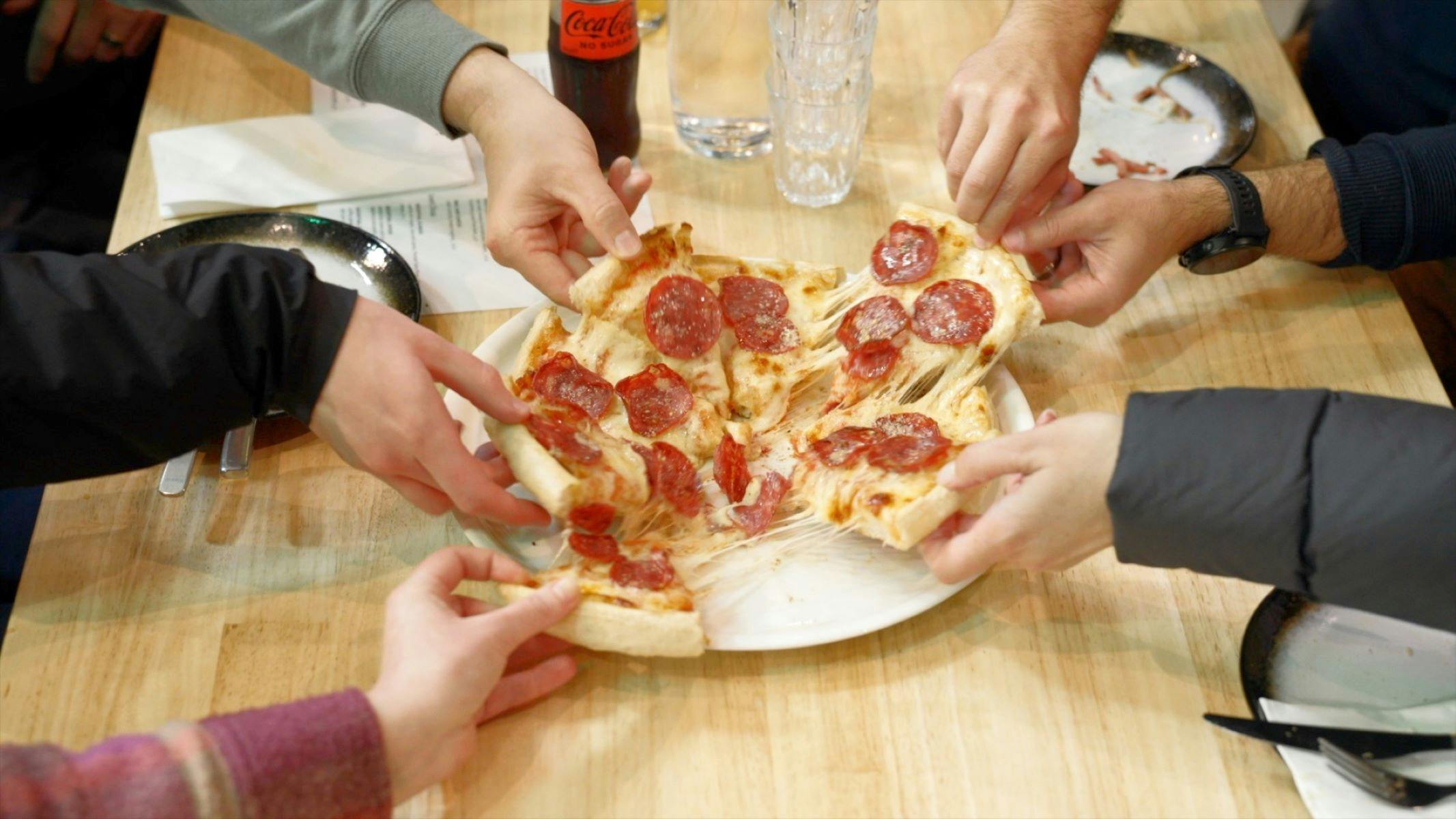 Hands grabbing pizza slices