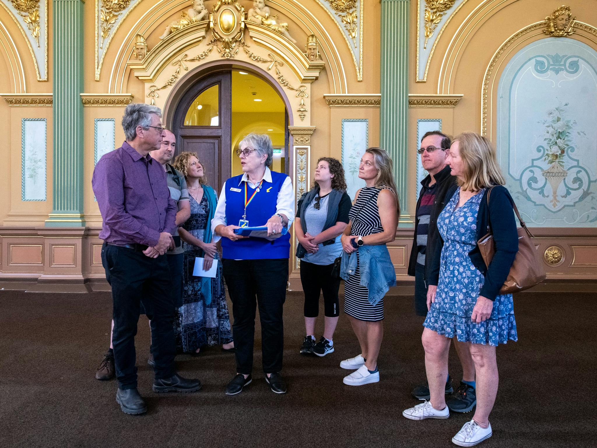 Guide showing engaged visitors the ornate plasterwork, murals and gold leaf work of the hall.