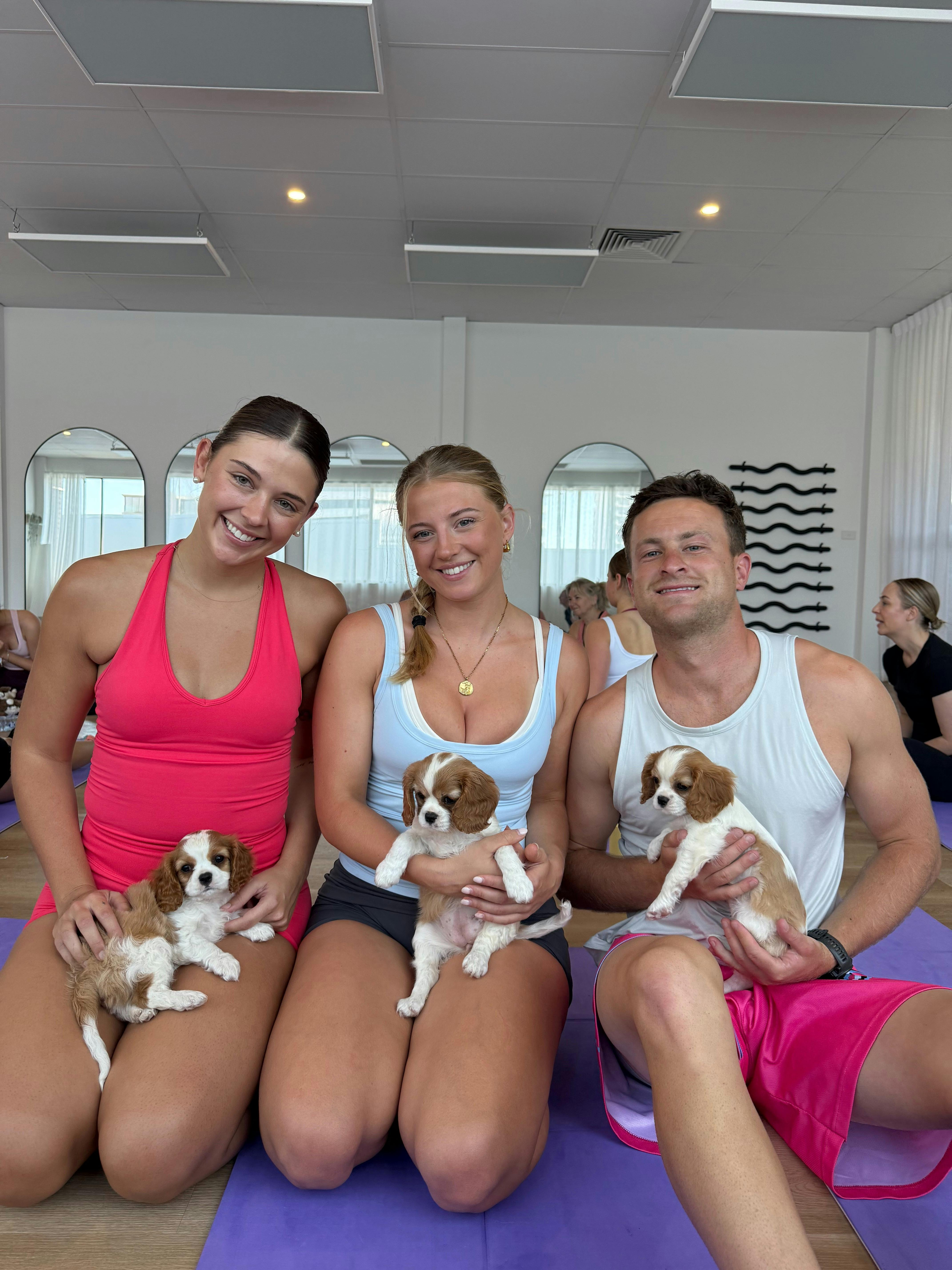 Friends enjoying puppy cuddles together at Yoga Paws on the Sunshine Coast.