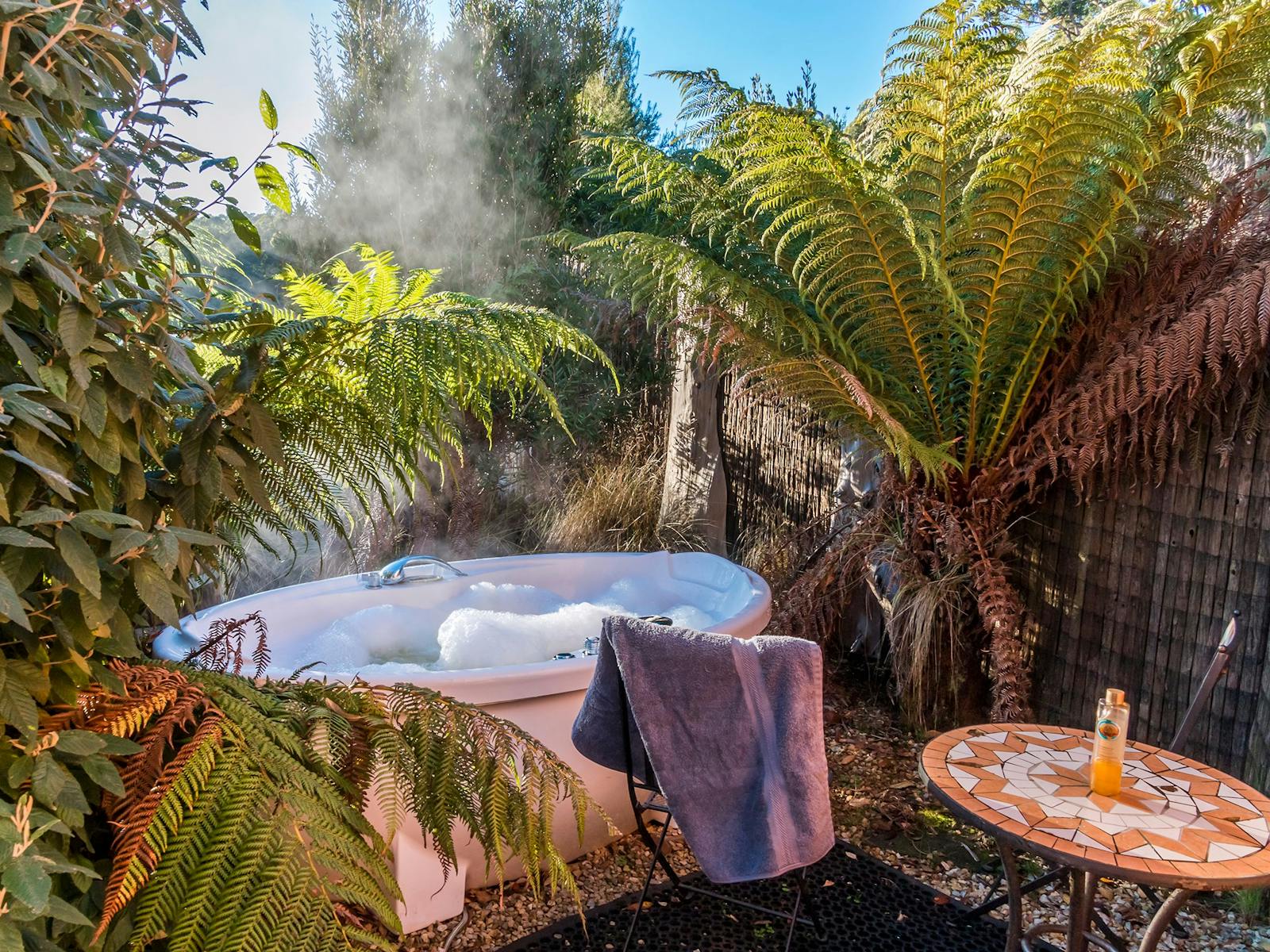Steam rising from the private outdoor spa surrounded by fern trees