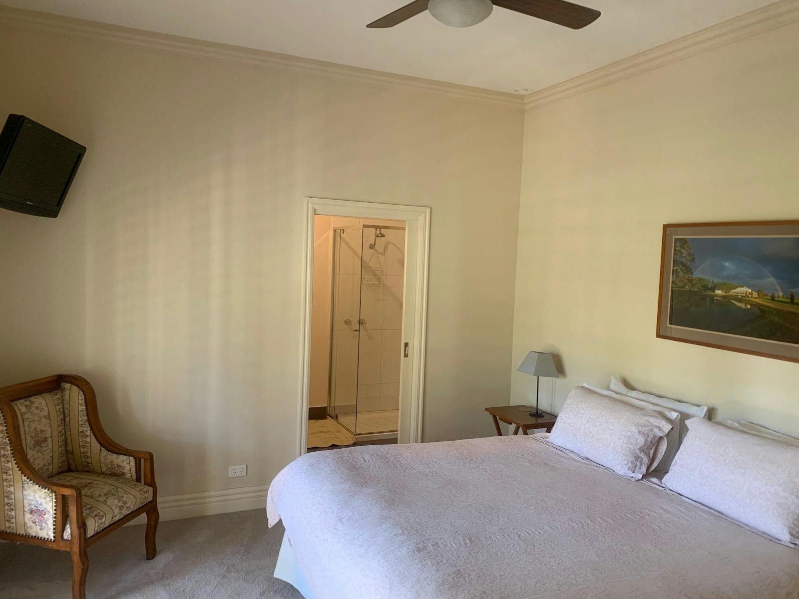 Buller room with bed and ensuite bathroom with a painting on the wall and a chair