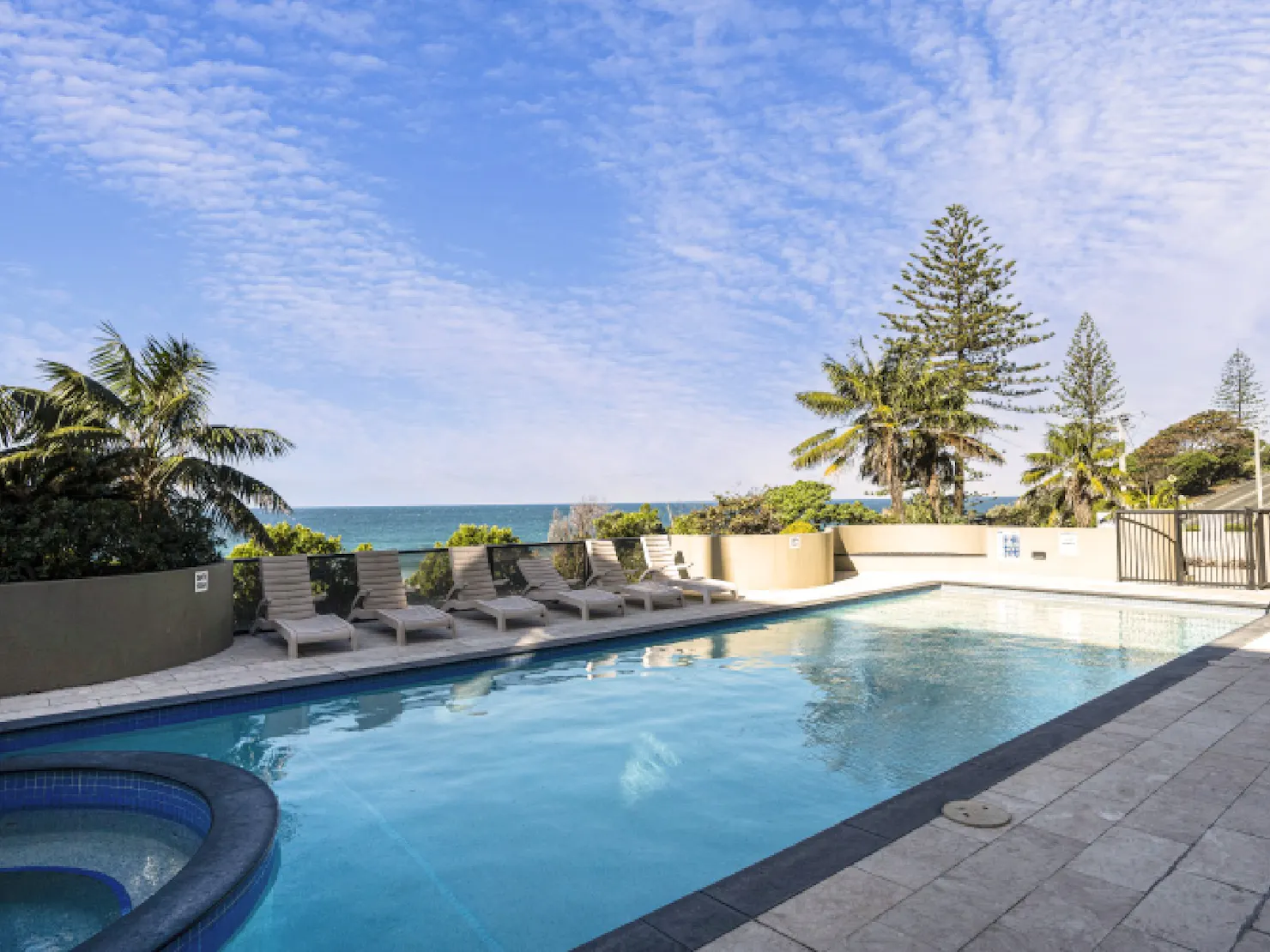 Shared Resort pool with sun loungers and views of the Pacific Ocean