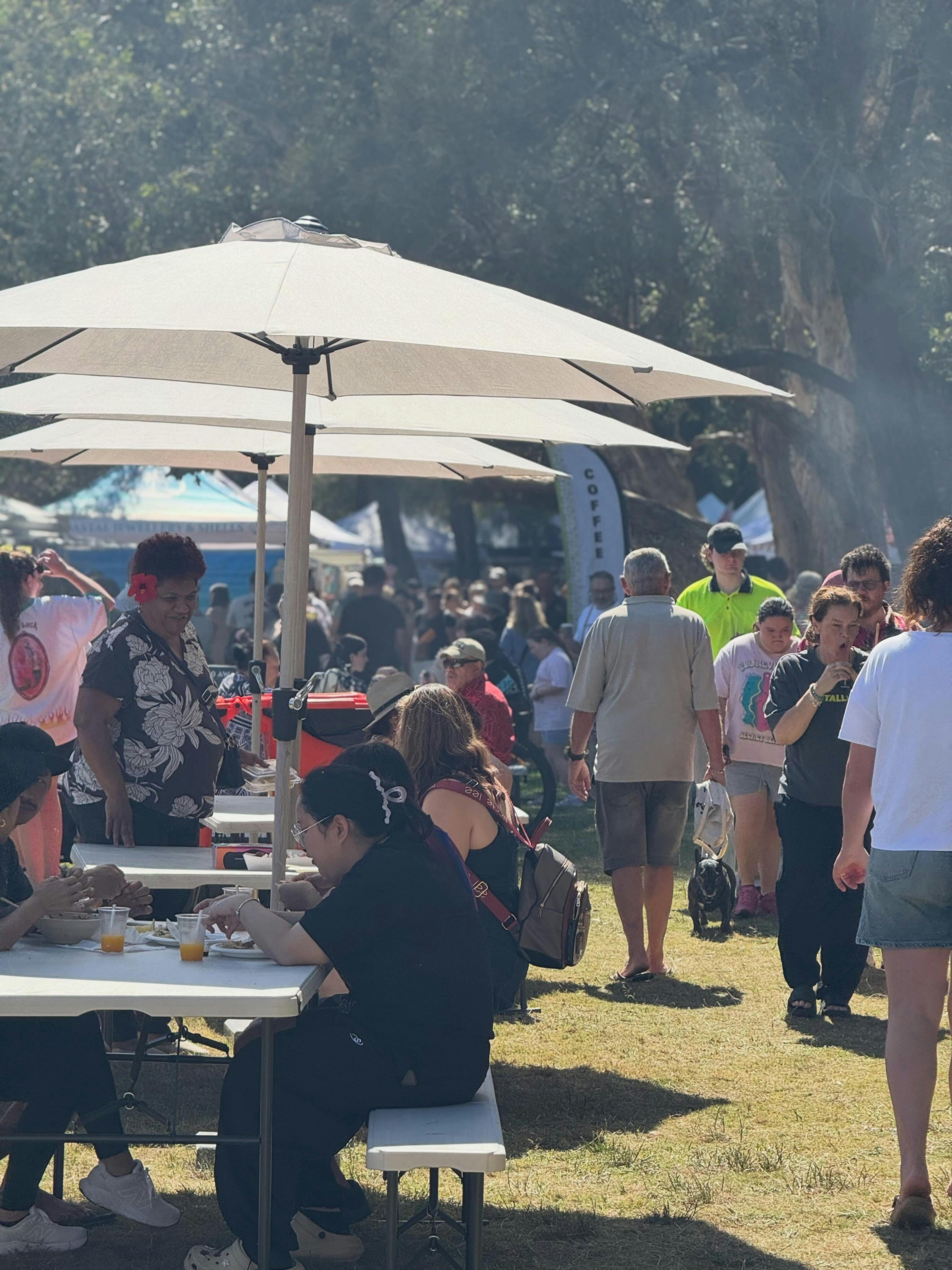 Visitors browsing outdoor market stalls beneath white gazebos at Long Jetty Markets