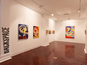 Gallery space with colourful paintings on the walls